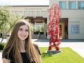 Kellie Gillespie next to her sculpture, connected, in front of the green music center