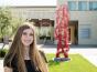 Kellie Gillespie next to her sculpture, connected, in front of the green music center